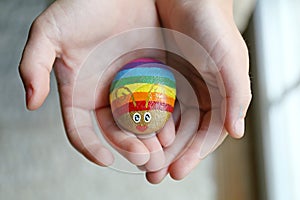 Child`s Hands Holding Rainbow Painted Bug Rock