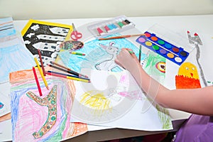 Child`s hands. Little left-handed child drawing with pencils. Top view, education painting, drawing concept.