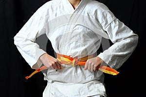 Child`s hands making a bow on karate belt