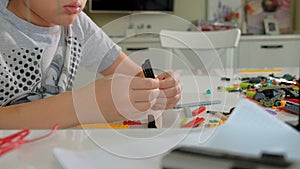 Child`s hands playing with a construction toy set, smart kid, plastic bricks