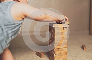 The child`s hands pushed the brick and destroyed the tower. Janga wooden box. An imbalance. destruction of blocks. Mistake.