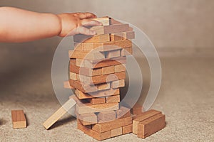 The child`s hands pushed the brick and destroyed the tower. Janga wooden box. An imbalance. destruction of blocks. Mistake.