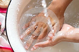 ChildÃ¢â¬â¢s hands under white bowl with water upon water stream