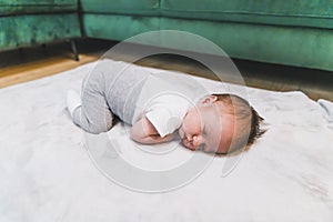 Child& x27;s innocence concept. Soft gray blanket for newborn babies being used by sleeping little caucasian baby boy in