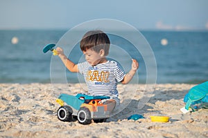 Child's Joyful Beach Adventure. Baby boy playing on the beach with a toy truck