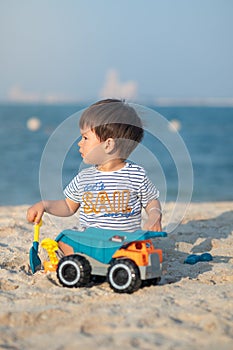 Child's Joyful Beach Adventure. Baby boy playing on the beach with a toy truck