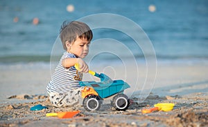 Child's Joyful Beach Adventure. Baby boy playing on the beach with a toy truck