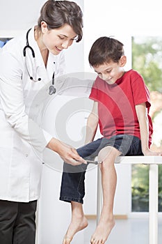 Child's neurologist testing knee reflex photo