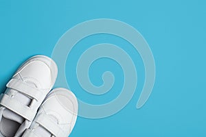 Child`s new white sport shoes or sneakers on the light blue pastel background