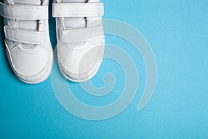 Child`s new white sport shoes or sneakers on the light blue pastel background