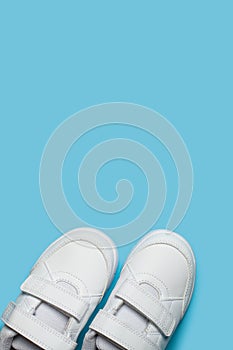 Child`s new white sport shoes or sneakers on the light blue pastel background