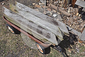 A child`s old red wagon loaded with weathered pieces of wood