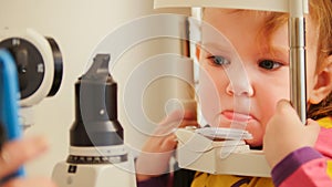 Child`s optometry concept - little girl angry when checks eyesight in eye ophthalmological clinic