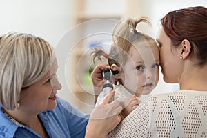 Child`s otolaryngologist doing ear examination of little kid