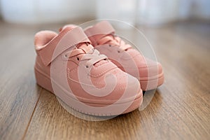 Child\'s pink sneakers on wooden floor. Cute girl\'s shoes on floor