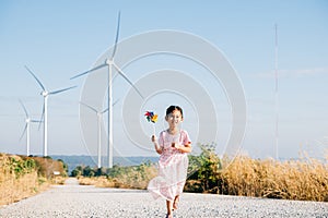 Child& x27;s playful exploration by windmills, little girl runs with pinwheels