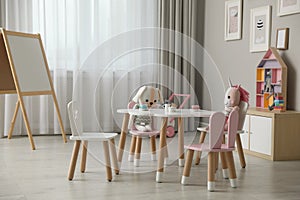 Child`s room interior with stylish table, chairs and toys