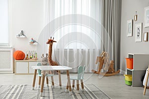 Child`s room interior with stylish table, chairs and toys