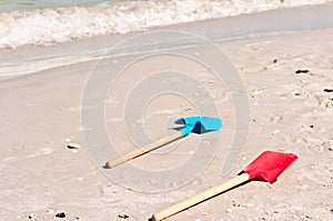 Child`s shovels, on shoreline, of tropical beach