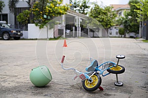 The child`s small bicycle fell to the ground with a helmet