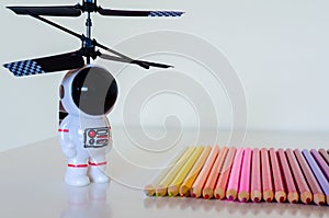 Child's Toy Spaceman looking towards a set of colorful pencil cr