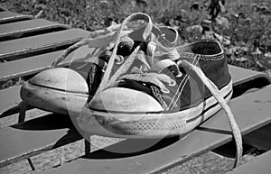 Child`s used shoes with loose laces on the park bench