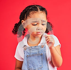 Child, sad and finger injury with plaster on isolated red background for cut, sore and insect bite. Upset, unhappy and