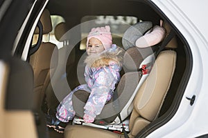 Child safety seat chair with baby girl is on back seat of car