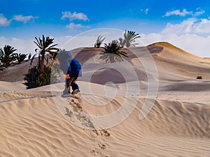 child in the Sahara desert plays with the sand of the dunes, tourist on vacation