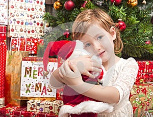 Child with santa doll in front of christmas tree