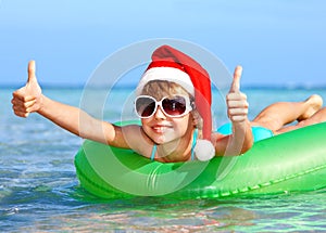 Child in santa hat floating on inflatable ring.