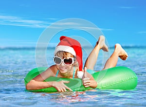 Child in Santa hat floating at sea.