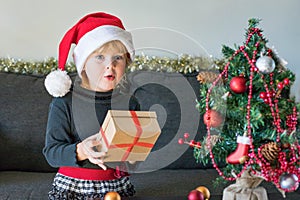 Child in santa hat holding christmas gift box. Christmas and New Year celebration