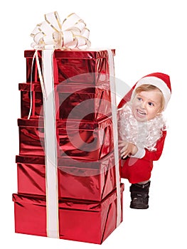 Child in santa hat by stack gift box.