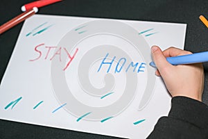 Child school guy drawing stay home slogan on a paper in covid19 pandemic disease,kids care