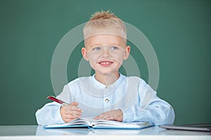 Child at school. Kid is learning in class on background of blackboard. Pupil near chalkboard during lesson at primary