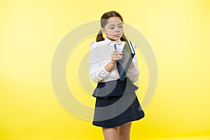 Child school uniform smart kid hold textbook. Girl happy face carry textbook yellow background. Child girl school