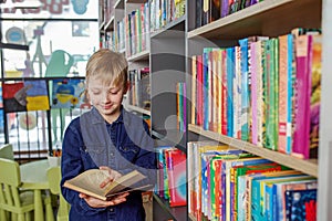 Child schoolboy reading book in library or bookstore. Concept of back to school and education