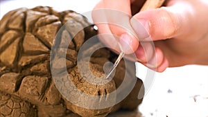 Child is scratching the texture of the scales on handmade turtle toy from clay