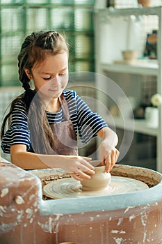 Child sculpts from clay pot. modeling on potter wheel.