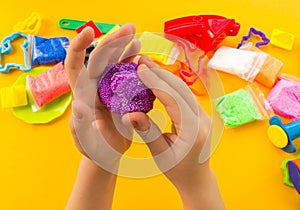 The child sculpts hands of colored clay. Material and tools for creativity