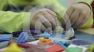 Child sculpts a sculpture made of coloured clay