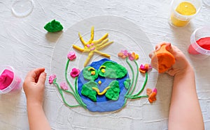 Child sculpturing plasticine planet for earth day. Protection of environment, Save our planet. Ecology concept.