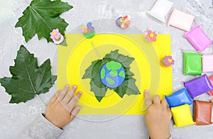 Child sculpturing plasticine planet for earth day. Protection of environment, Save our planet. Ecology concept. Concept of art
