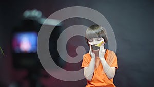 The child seals his mouth with adhesive tape in front of the video camera.