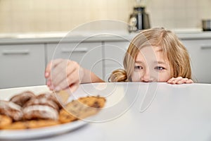 Child secretly taking american cookies from plate.