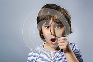 Child See Through Magnifying Glass, Kid Eye Looking with Magnifier Lens over Gray