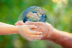 Child and senior holding Earth planet in hands