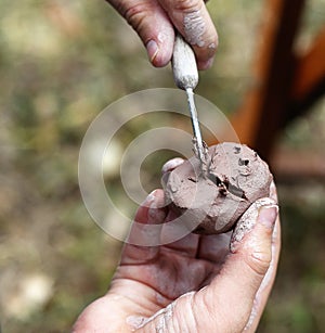 A child is shaping brown clay using specialty tools in a workshop during an art festival in Gulfport, Florida
