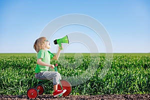 Child shouting through loudspeaker against blue summer sky